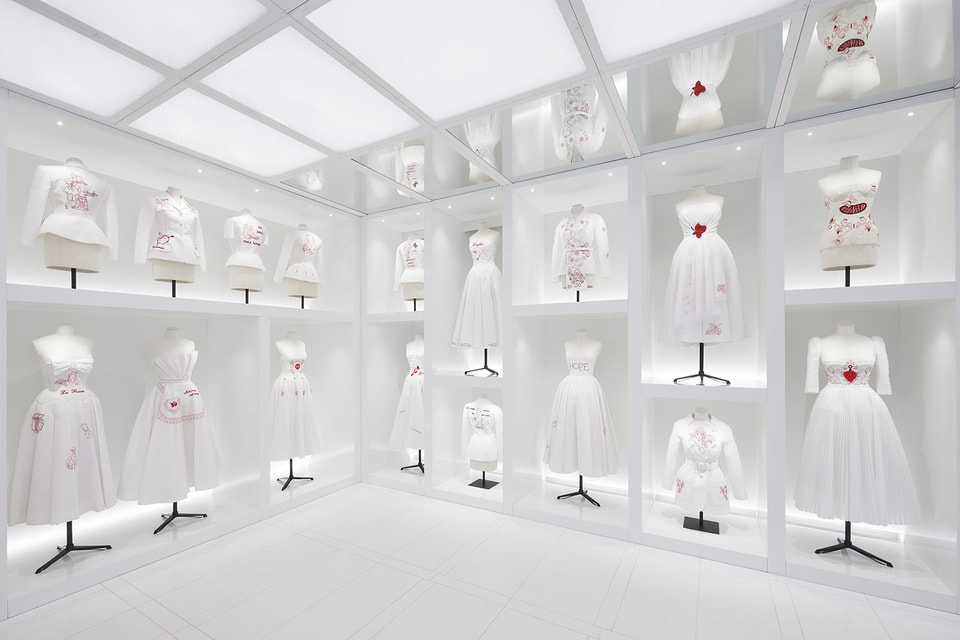 Отдельная комната выставки отведена под работы художницы Элины Шове, которая поместила на белые муслиновые платья концептуальные лозунги, вышитые красной нитью